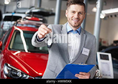 Lächelnde Verkäufer Übergabe Autoschlüssel Stockfoto