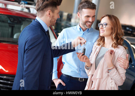 Glückliches Paar Schlüssel vom Verkäufer bekommen Stockfoto