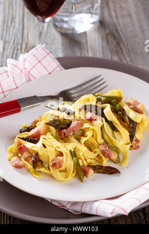 Italienische Pasta Carbonara mit Spargel. Auf rustikalem Holztisch. Stockfoto