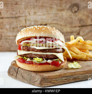 frische leckere Burger und Kartoffeln auf Holzbrett Stockfoto