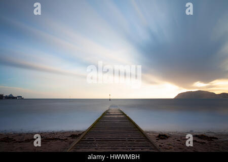 Langzeitbelichtung Landschaft des Sonnenaufgangs über little Orme, Llandudno Pier, Holzsteg und Meer bei dem Küstenort Llandudno in Nord-Wales Stockfoto