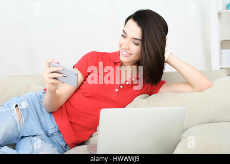 Lächelnde junge Frau auf couch Stockfoto