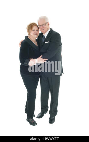 Ein schönes älteres Ehepaar stehen in Anzügen, umarmen einander in voller Länge für weißen Hintergrund isoliert. Stockfoto