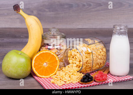 Corn Flakes, Müsli, Orange, Banane, Apfel, Joghurt und kandierten Früchten auf einem hölzernen Hintergrund Stockfoto