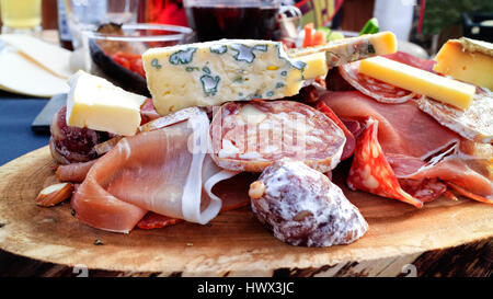 Kürzungen von blau, Kuh, Ziegenkäse, Schweineschinken, geräuchertem Fleisch, Salami, Fette Wurst serviert auf ein Stück Holz zum Mittagessen im apres Ski Chalet Bistro. Stockfoto