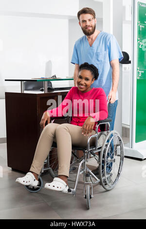 Porträt des Lächelns weibliche Patienten sitzen im Rollstuhl und Krankenschwester im Krankenhaus hinter Stockfoto