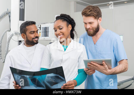 Männliche und weibliche Mediziner mit Röntgen und digitale Tablet im Untersuchungsraum Stockfoto