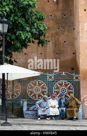Chefchaouen, Marokko.  Männer sprechen auf einer Bank in der Plaza Outa El-Hamam. Stockfoto