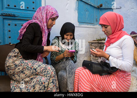 Chefchaouen, Marokko.  Junge arabische Frauen überprüft ihre Handys. Stockfoto