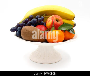 Obst Teller Schale - Bananen, dunkle blaue Trauben, Kiwi, Äpfel, Bananen, Mandarinen mit weißem Hintergrund Blatt - Keramik-Keramik Teller - isoliert Stockfoto