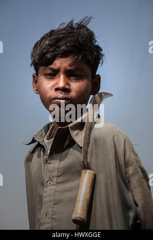 Kleiner Junge, ein Feldarbeiter, der während der Ernte in Sindh, Pakistan, mit seiner Sichel auf der Schulter posiert Stockfoto