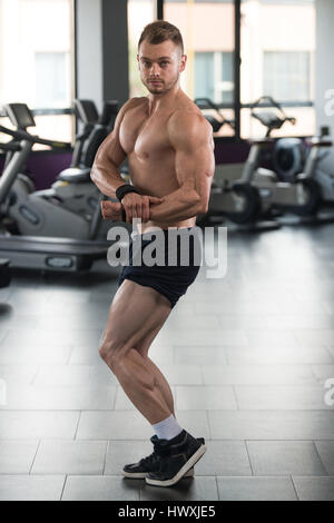 Gesunder Mensch stehen stark In der Turnhalle und beugen Muskeln - muskulöse athletische Bodybuilder Fitness Model posiert nach Übungen Stockfoto