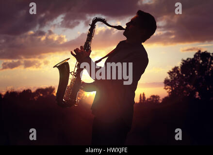 Saxophonist oder Saxophonistin Sax gegen Sonnenuntergang durchführen Stockfoto