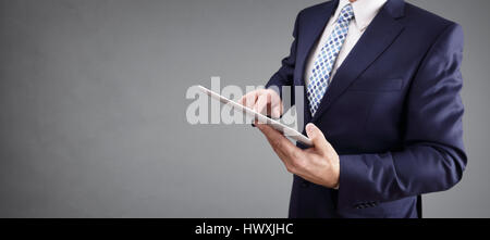 Geschäftsmann mit Tablet-Computer und grauem Hintergrund zum Kopieren Stockfoto