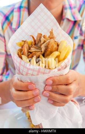 Mädchen halten griechische Gyros mit Pommes frites hautnah auf Tisch Stockfoto