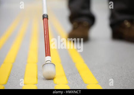Blinde Fußgänger zu Fuß und Erkennung von Markierungen auf taktile ebnet mit strukturiertem Boden Oberfläche Indikatoren für Blinde und sehbehinderte Menschen. Blindheit eine Stockfoto