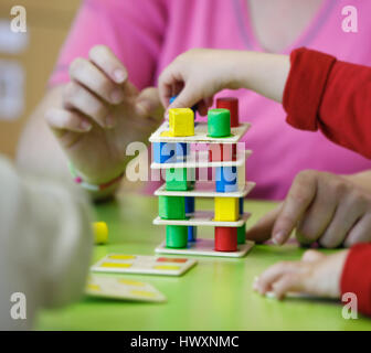 Kinder spielen mit hausgemachten, do it yourself Lernspielzeug, stapeln und Vermittlung von bunte Stücke. Brutto-lernen durch Erfahrung-Konzept, eine Stockfoto