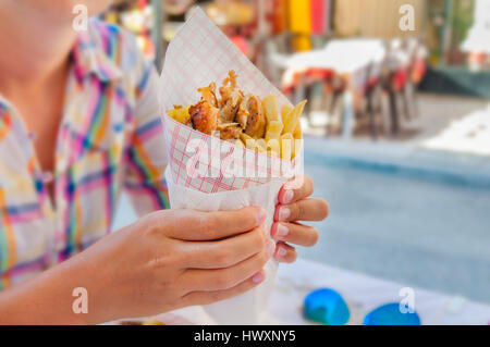 Mädchen halten griechische Gyros mit Pommes frites hautnah auf Tisch Stockfoto