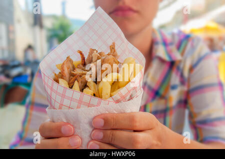 Mädchen halten griechische Gyros mit Pommes frites hautnah auf Tisch Stockfoto