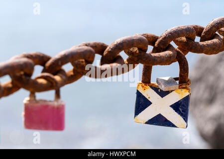 Ein Vorhängeschloss Lovelock an eine alte Absperrkette und lackiert in den Farben der schottischen Flagge oder St. Andrews Kreuz Stockfoto