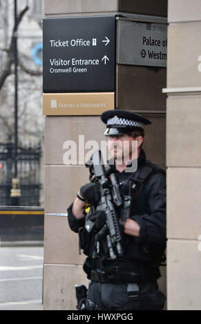 Ein bewaffneter Polizist steht in der Nähe von Westminster u-Bahnstation in London, nachdem sieben Menschen bei Razzien in London, Birmingham und anderswo verbunden mit dem Westminster-Terror-Anschlag verhaftet wurden. Stockfoto