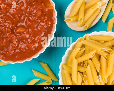 Ungekocht Schüssel mit Penne-Nudeln mit Tomaten auf blauem Grund Stockfoto