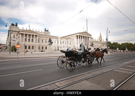 Eine Pferdekutsche namens Fiaker Pässe durch das österreichische Parlament auf der Ringstraße in Wien. Stockfoto