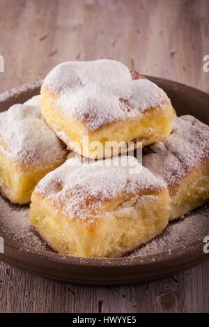 Vertikale Foto mit fünf Portionen an traditionellen hausgemachten Kuchen von süßen Quark gefüllt. Kuchen auf braunen Ton Platte gesetzt und fallenden Ei Stockfoto