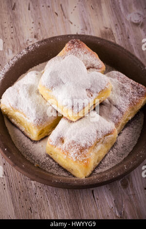 Vertikale Foto mit fünf Portionen an traditionellen hausgemachten Kuchen von süßen Quark gefüllt. Kuchen auf braunen Ton Platte gesetzt und fallenden Ei Stockfoto