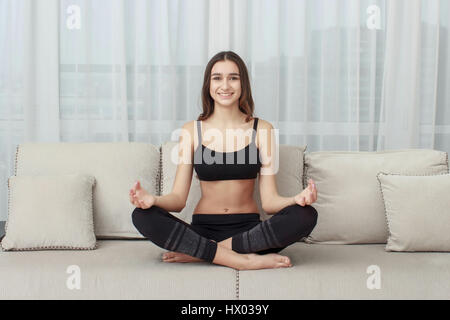 Frau, meditieren im Lotussitz auf der couch Stockfoto