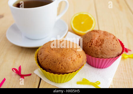 Leichten Zitronen Cupcakes Muffins auf hölzernen Hintergrund und eine Tasse Tee. Stockfoto