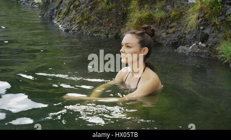 Erhöhte Ansicht der Frau im Bikini sitzen in entfernten Pool Wasser Stockfoto