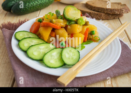 Gemüseeintopf (Kartoffeln, Spargel, Karotten, Rosenkohl, Mais, Erbsen, Wirsing, Brokkoli) in einem weißen Teller. Vegan. Stockfoto