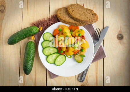 Gemüseeintopf (Kartoffeln, Spargel, Karotten, Rosenkohl, Mais, Erbsen, Wirsing, Brokkoli) in einem weißen Teller. Vegan. Stockfoto