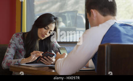 Selektiven Fokus Blick abgelenkt Freund und Freundin, die mit Smartphones am Tisch im café Stockfoto