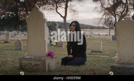 Traurige nachdenkliche Frau sitzt am Grab in einsamen Friedhof Stockfoto