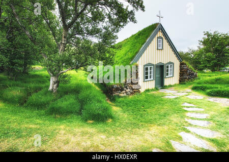 Eine kleine hölzerne Kirche und Friedhof Hofskirkja Hof, Skaftafell Island. Malerischen Sonnenuntergang durch Baumkronen. Stockfoto