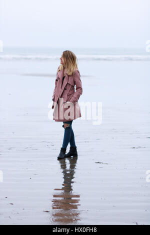 Junge blonde Frau trägt rosa Mantel auf Black Rock Sands Beach Stockfoto