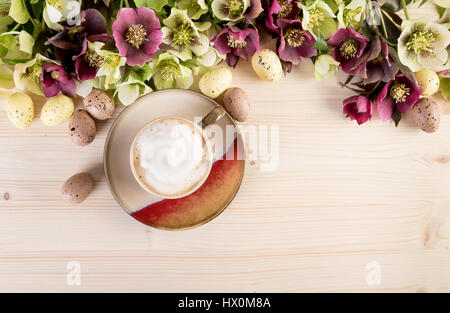 Kaffee Tasse Cappuccino mit Frühlingsblumen und Easter Egg auf hellem Holz Hintergrund. Ansicht von oben, Text-Raum. Stockfoto