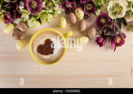 Kaffee Tasse Cappuccino mit Oster-Deko auf leichte Holztisch. Herz-Form-Schaum, Ansicht von oben. Stockfoto