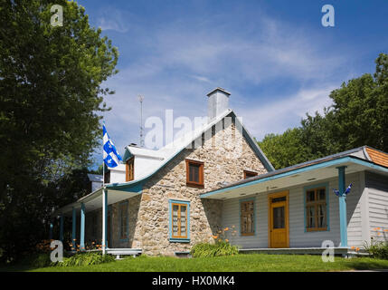 1810 altes Feldsteinhaus mit blauen und orangefarbenen Zierleisten im Sommer. Stockfoto