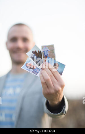 Mannes Hand mit vier Sofortbilder von sich selbst, Nahaufnahme Stockfoto