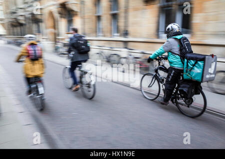 Deliveroo Food Kurier eilt durch die Straßen von Cambridge, UK, Speisen zum Mitnehmen an Kunden zu liefern, die auf ihrem Smartphone zu bestellen. Stockfoto