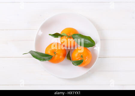 Teller mit frischen Mandarinen mit Blättern auf weißem Hintergrund Stockfoto