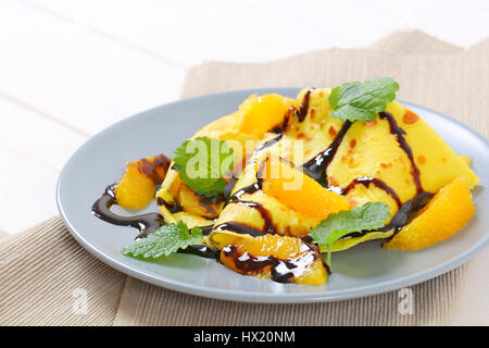Teller mit Pfannkuchen mit Orangen und Schokolade Topping auf Beige Tischset - Nahaufnahme Stockfoto
