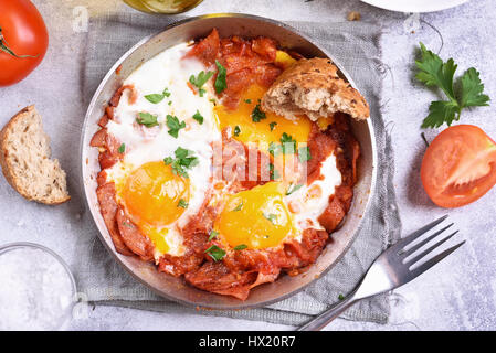 Frühstück mit gebratenen Eiern, Tomaten und Speck in Pfanne, Ansicht von oben, Nahaufnahme Stockfoto