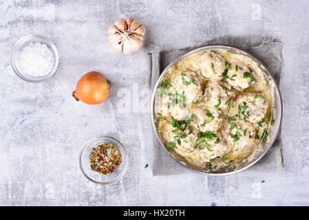 Gericht zum Abendessen. Fleischbällchen mit weißer Soße in Pfanne auf Stein Hintergrund, Ansicht von oben Stockfoto