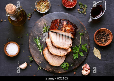 In Scheiben geschnitten gegrilltes Schweinefleisch Grillfleisch auf Holzbrett auf dunklem Hintergrund, Ansicht von oben Stockfoto