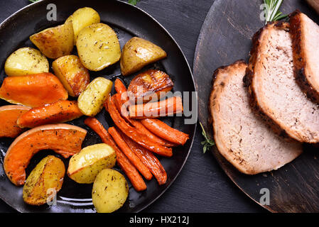 Gebratenes Gemüse in der Pfanne schwenken und in Scheiben geschnitten, gegrilltes Fleisch, Ansicht von oben. Gemüse im Fokus Stockfoto