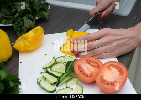 Frauenhand Tomate hinter frisches Gemüse schneiden. Stockfoto